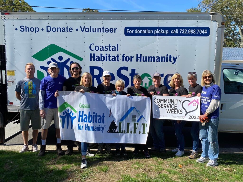 A group of people standing in front of a habitat for humanity sign.