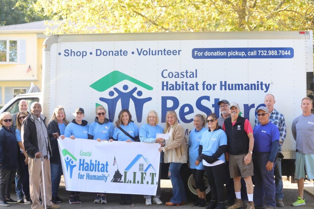 A group of people standing in front of a habitat for humanity sign.