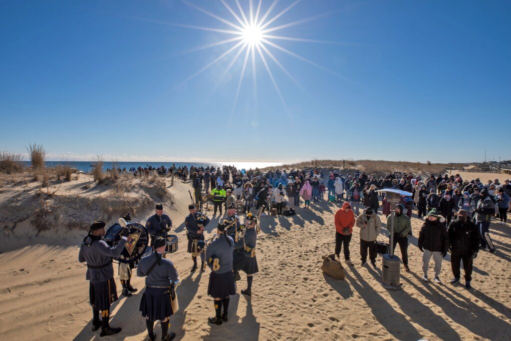 A crowd of people standing on top of a sandy beach.